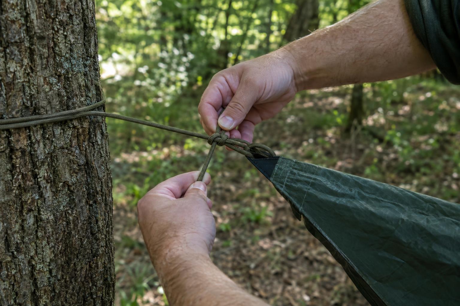 Tying a tarp shelter corner to a tree with cordage
